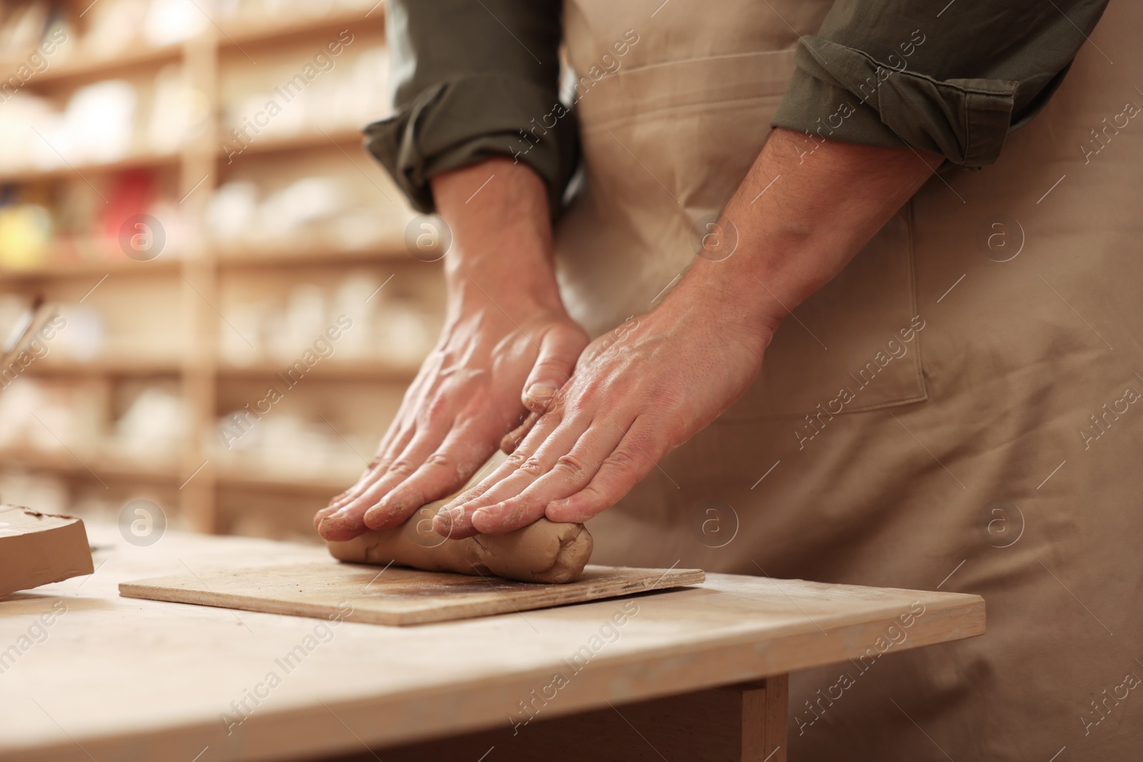 Photo of Man crafting with clay at table indoors, closeup