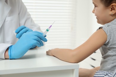 Children's hepatitis vaccination. Doctor giving injection to little girl in clinic, closeup