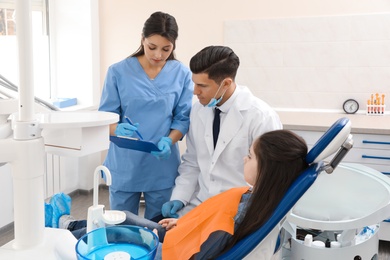 Professional dentist and assistant working with little girl in clinic