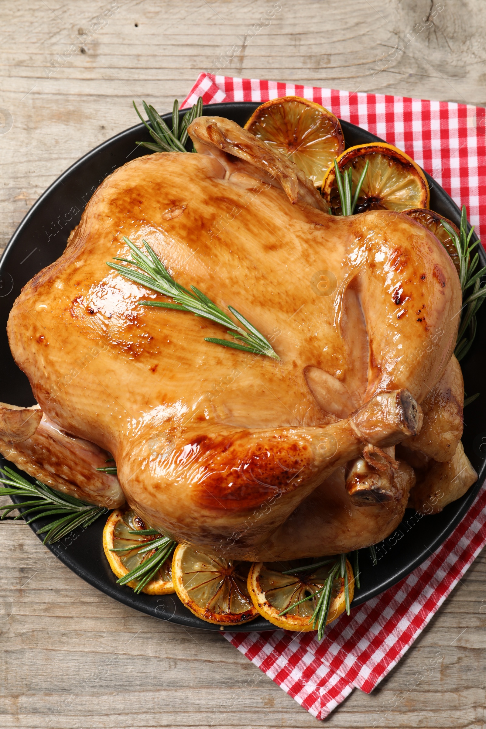 Photo of Tasty roasted chicken with rosemary and lemon on wooden table, top view