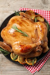 Tasty roasted chicken with rosemary and lemon on wooden table, top view