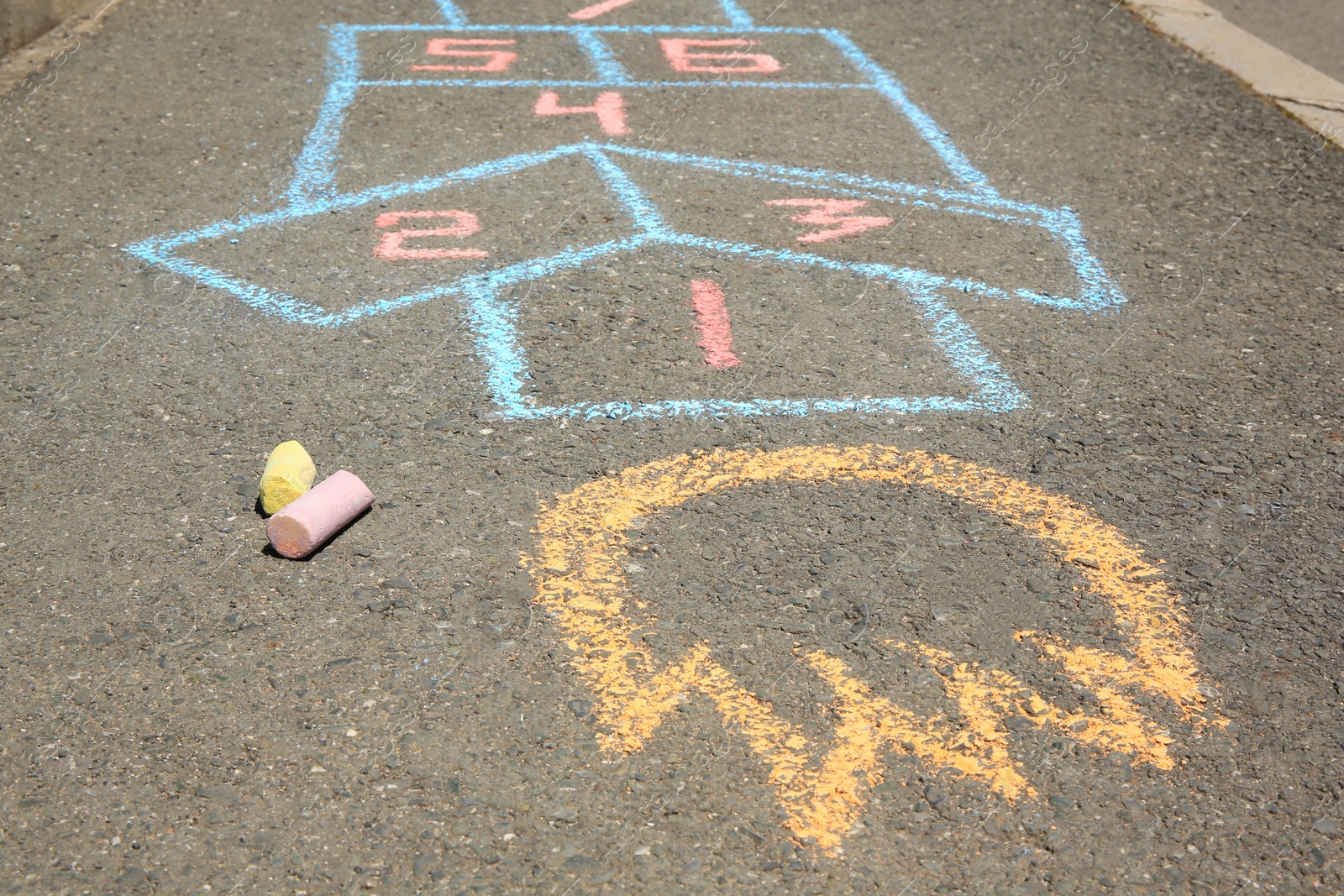 Photo of Hopscotch drawn with colorful chalk on asphalt outdoors, closeup