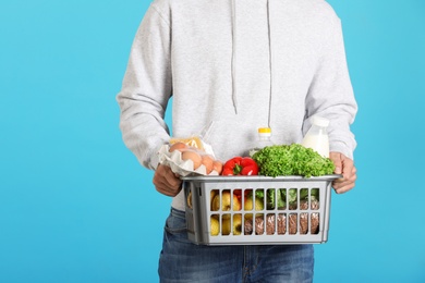 Man holding basket with fresh products on color background, closeup. Food delivery service