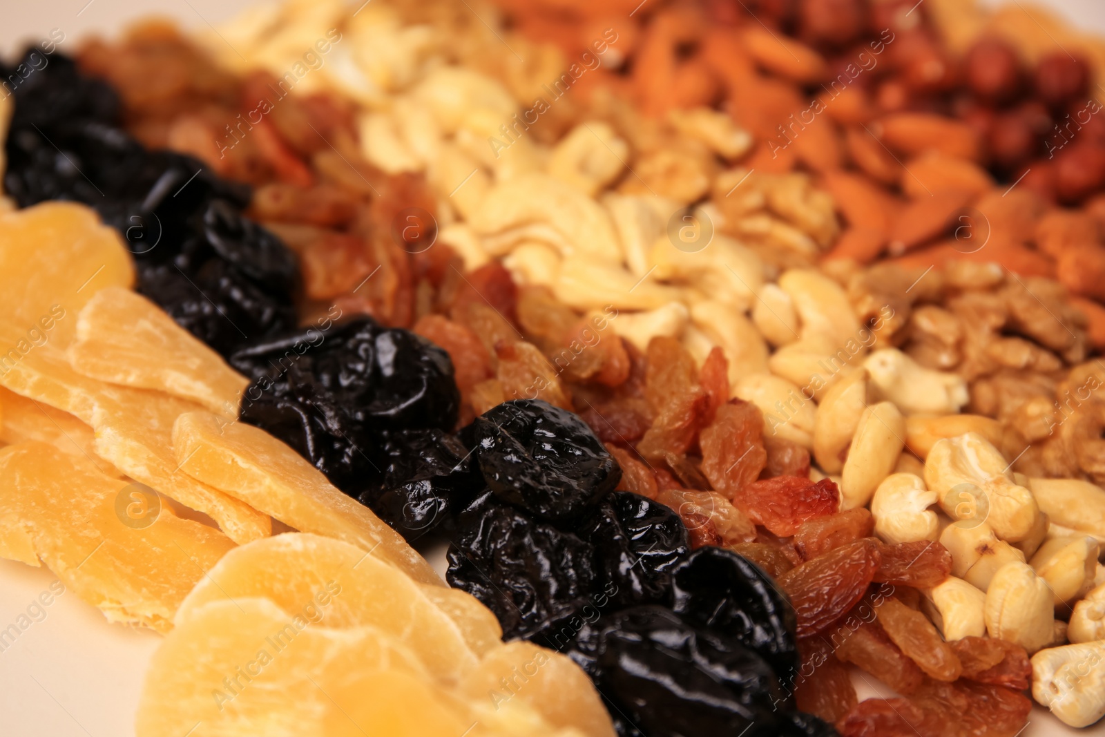 Photo of Mix of delicious dried nuts and fruits on beige background, closeup