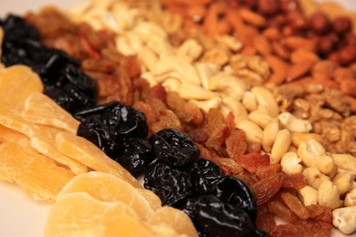 Mix of delicious dried nuts and fruits on beige background, closeup