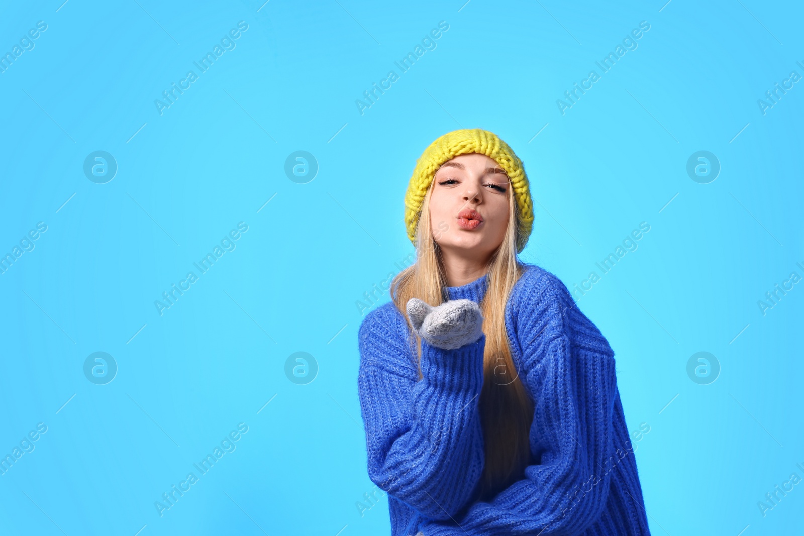 Photo of Portrait of emotional young woman in stylish hat, sweater and mittens on color background, space for text. Winter atmosphere