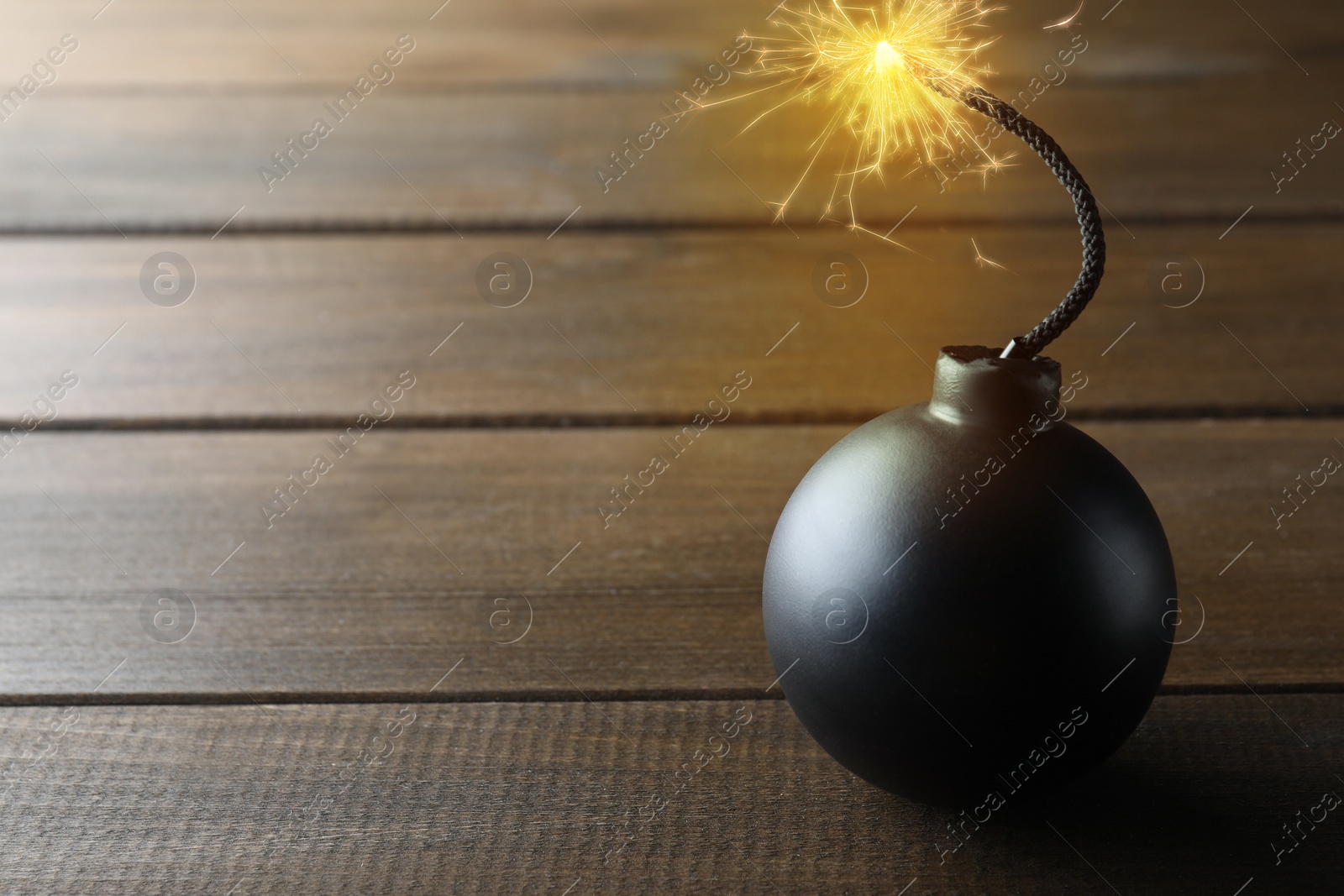 Image of Old fashioned black bomb with lit fuse on wooden table, space for text