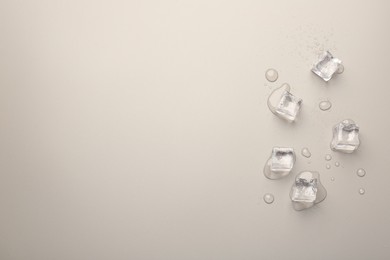 Melting ice cubes and water drops on light grey background, flat lay. Space for text