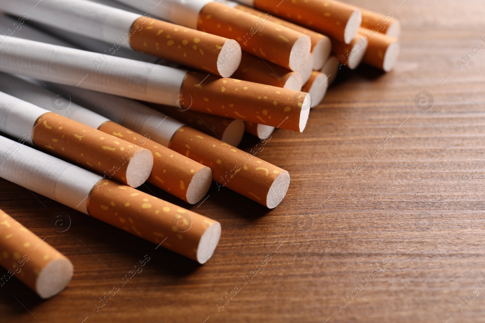 Photo of Pile of cigarettes on wooden table, closeup