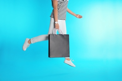 Photo of Woman jumping with paper shopping bag on color background. Mock up for design