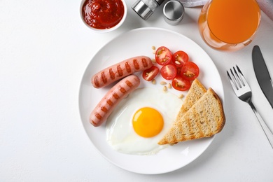 Tasty breakfast with fried egg and sausages served on white table, flat lay