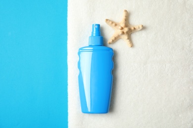 Photo of Bottle of sun protection body cream, starfish and towel on color background, top view with space for text