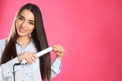 Happy woman using hair iron on color background. Space for text