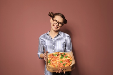 Attractive young woman with delicious pizza on color background