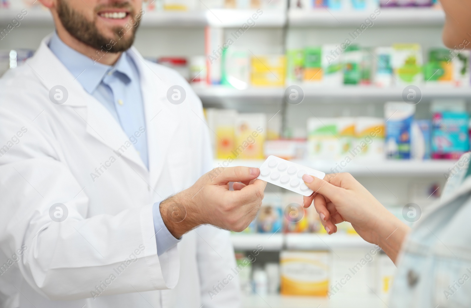 Photo of Professional pharmacist giving pills to customer in modern drugstore, closeup