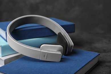 Photo of Modern headphones with hardcover books on grey table, closeup. Space for text