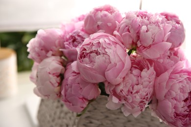 Photo of Basket with beautiful pink peonies in kitchen, closeup