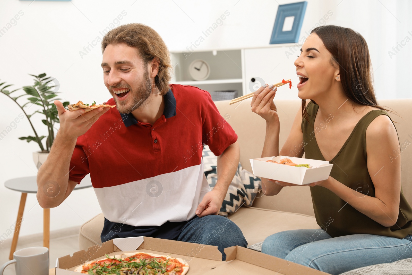 Photo of Young couple having lunch in living room. Food delivery