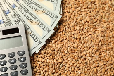 Photo of Dollar banknotes and calculator on wheat grains, closeup. Agricultural business