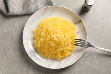 Plate of cooked spaghetti squash on gray background, top view