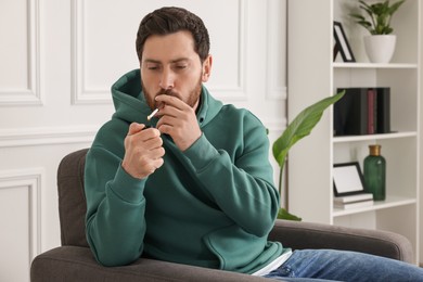 Photo of Man using cigarette holder for smoking indoors