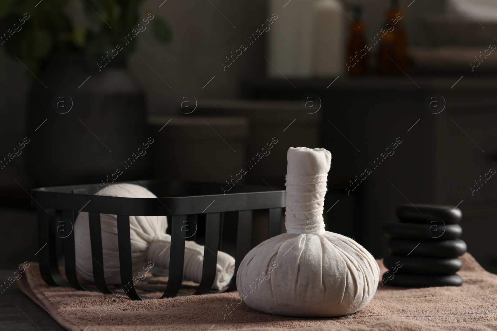 Photo of Herbal massage bags, stones and bath towel on table. Spa products