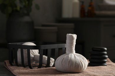 Herbal massage bags, stones and bath towel on table. Spa products