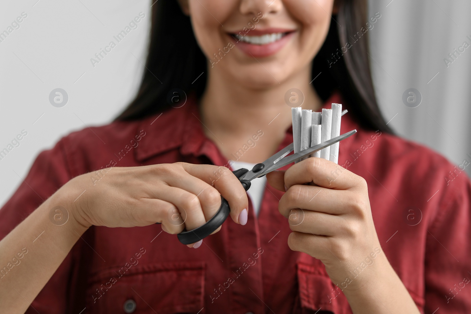 Photo of Stop smoking concept. Woman cutting cigarettes on light background, closeup