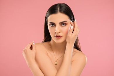 Beautiful woman with elegant necklace on pink background