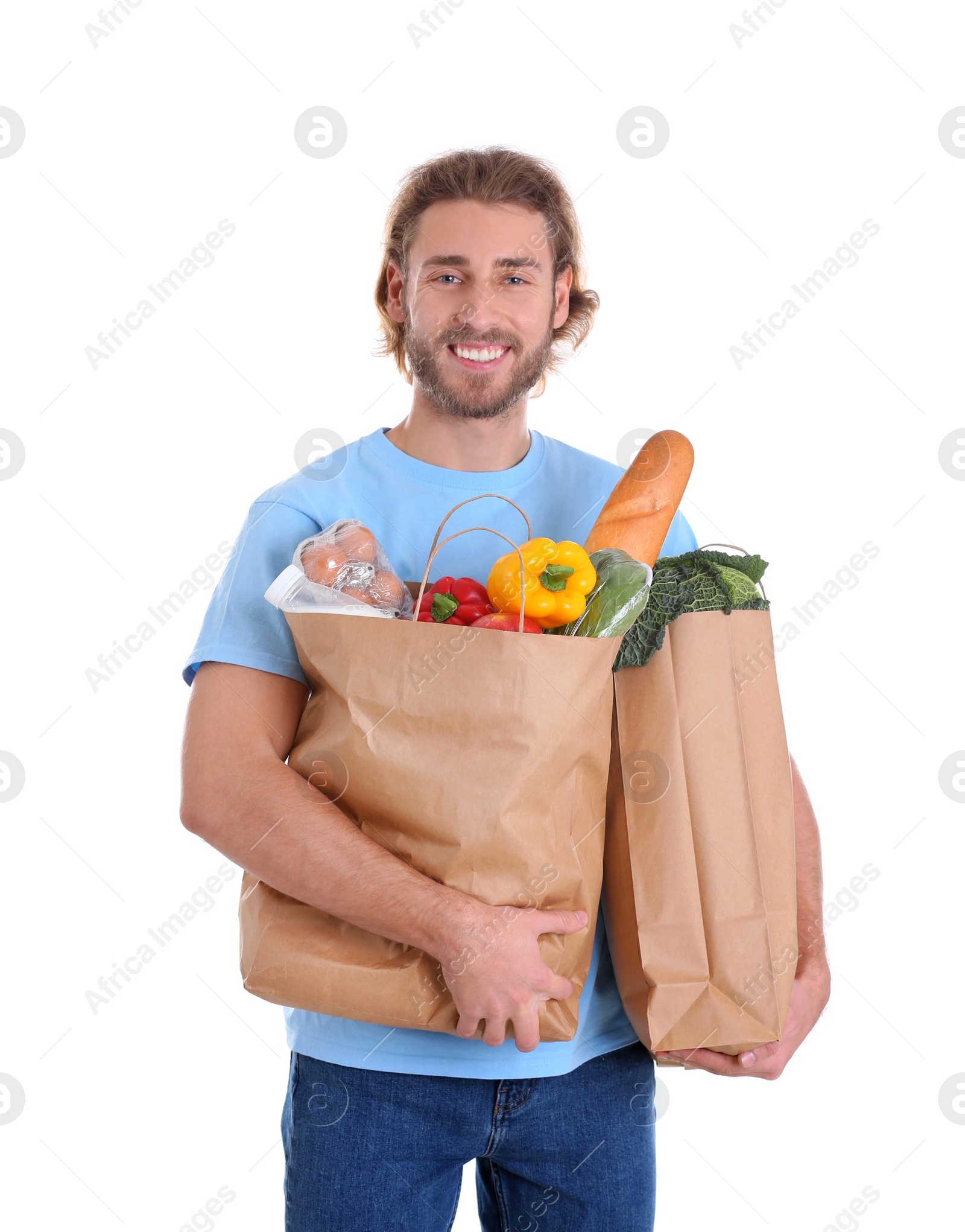 Photo of Delivery man holding paper bags with food products on white background