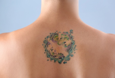 Beautiful tattoo on female back against color background