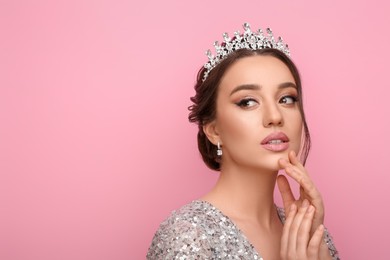 Photo of Beautiful young woman wearing luxurious tiara on pink background, space for text