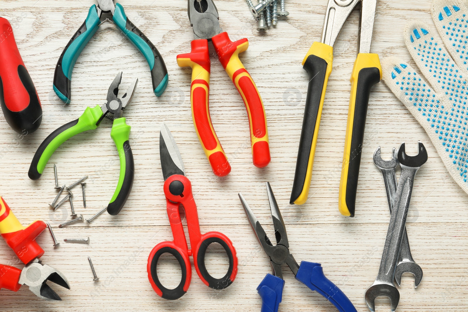 Photo of Different pliers, scissors and other tools for repair on wooden table, flat lay