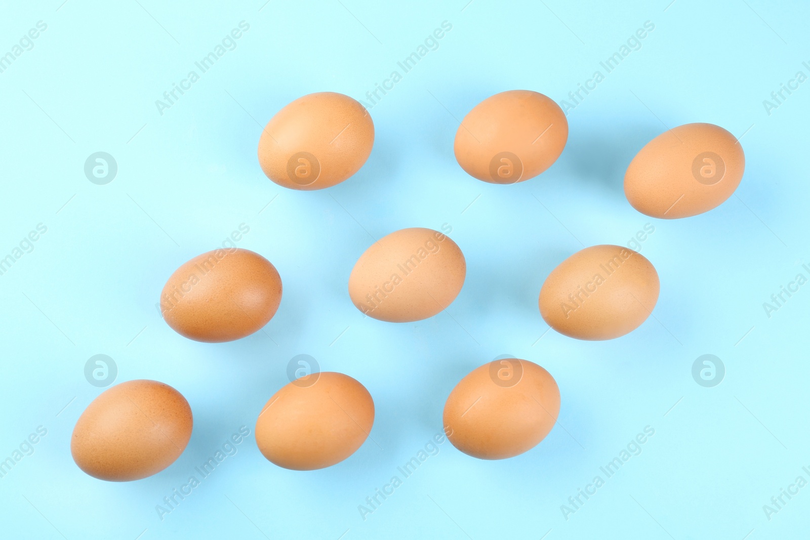 Photo of Raw chicken eggs on light blue background, flat lay