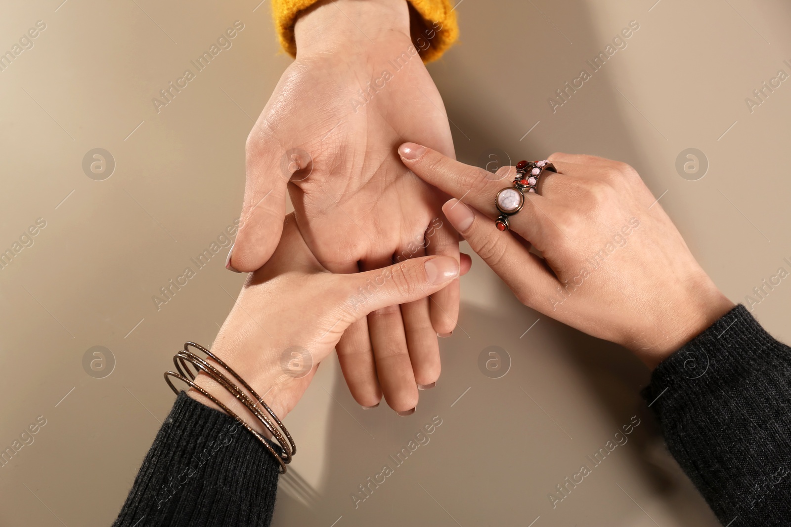 Photo of Chiromancer reading lines on woman's palm at table, top view