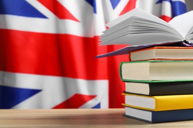Photo of Learning foreign language. Different books on wooden table against flag of United Kingdom, space for text