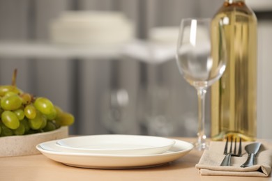 Photo of White plates, glass, cutlery and wine served for dinner on wooden table