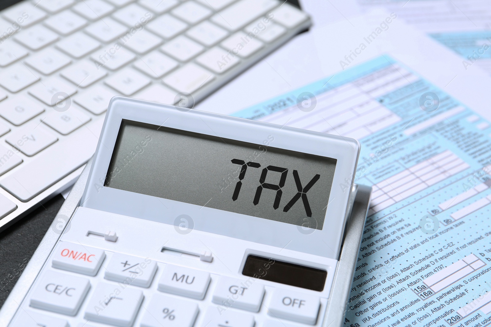 Image of Calculator with word Tax, document and keyboard on table, closeup