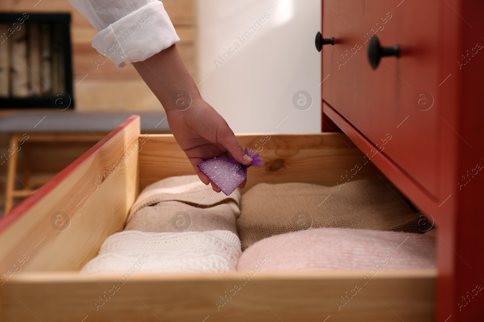 Photo of Woman putting scented sachet into drawer with clothes, closeup