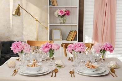 Stylish table setting with beautiful peonies and fabric napkins indoors