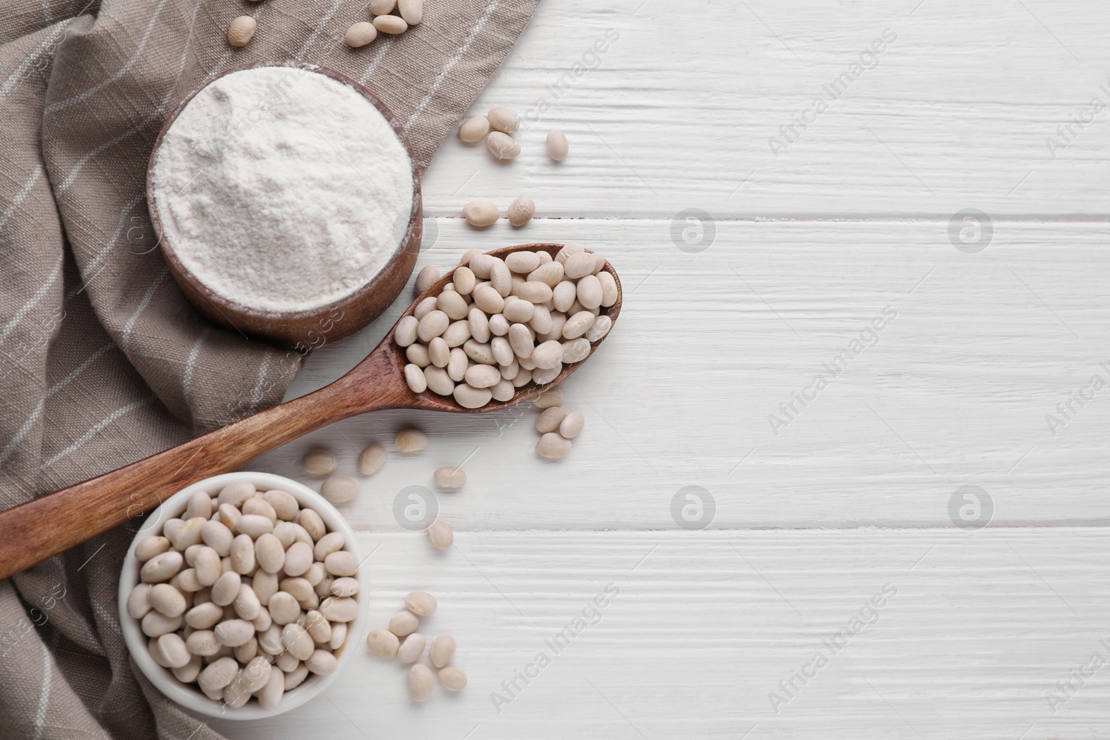 Photo of Kidney bean flour and seeds on white wooden table, flat lay. Space for text