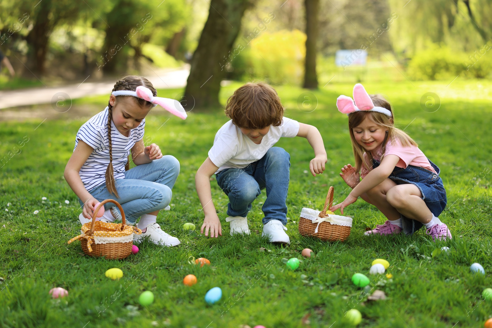 Photo of Easter celebration. Cute little children hunting eggs outdoors