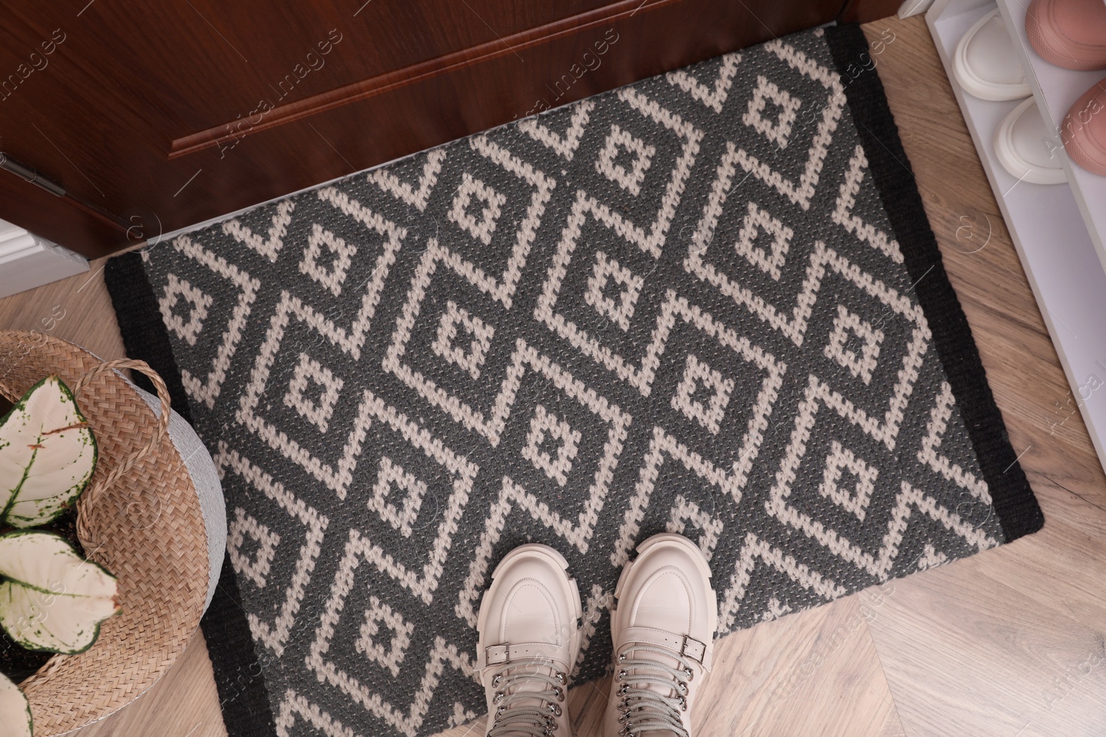 Photo of Stylish door mat with shoes on floor indoors, flat lay