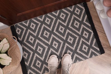 Photo of Stylish door mat with shoes on floor indoors, flat lay