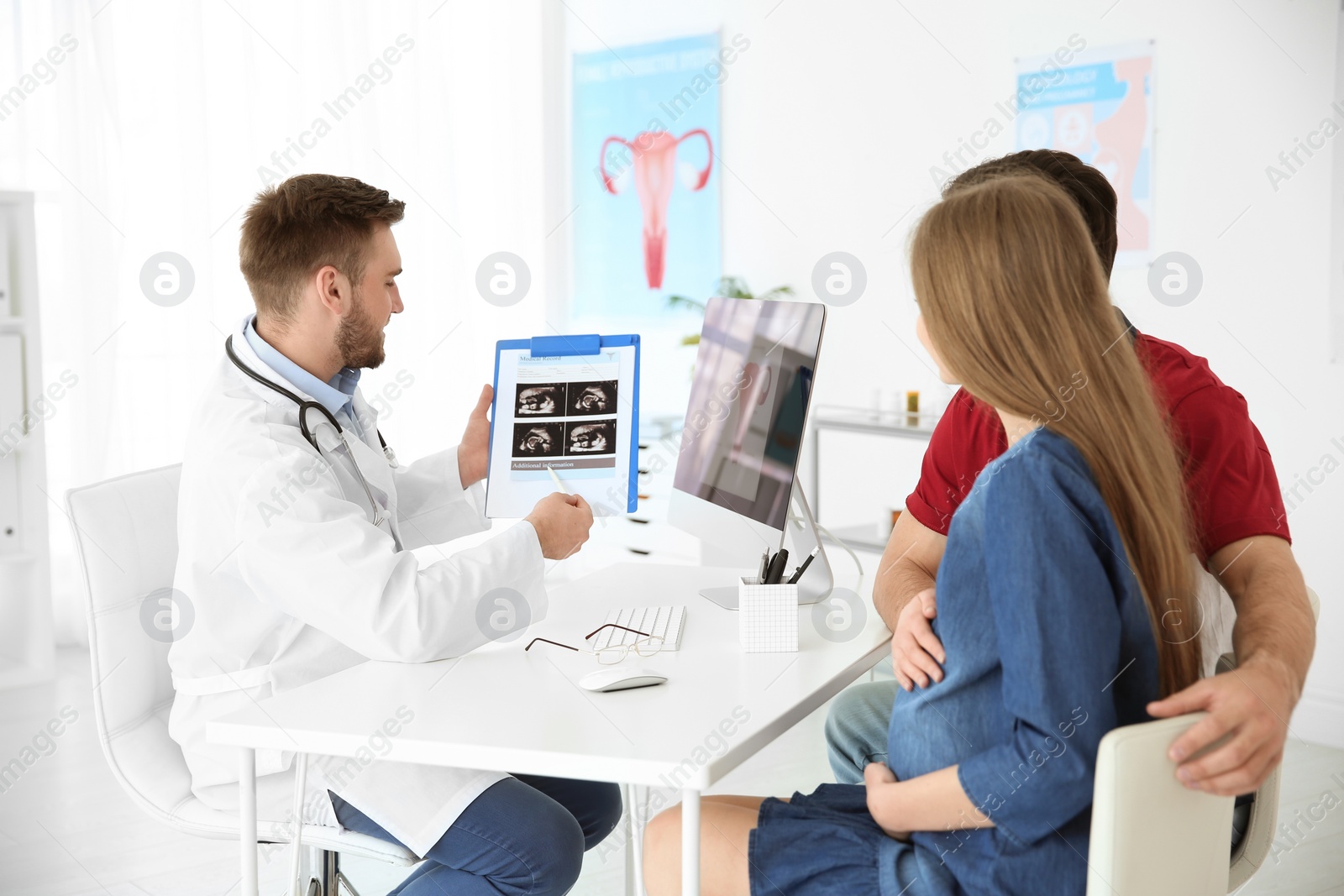 Photo of Gynecology consultation. Doctor showing ultrasound of baby to future parents in clinic