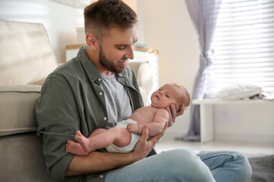 Photo of Father with his newborn son at home