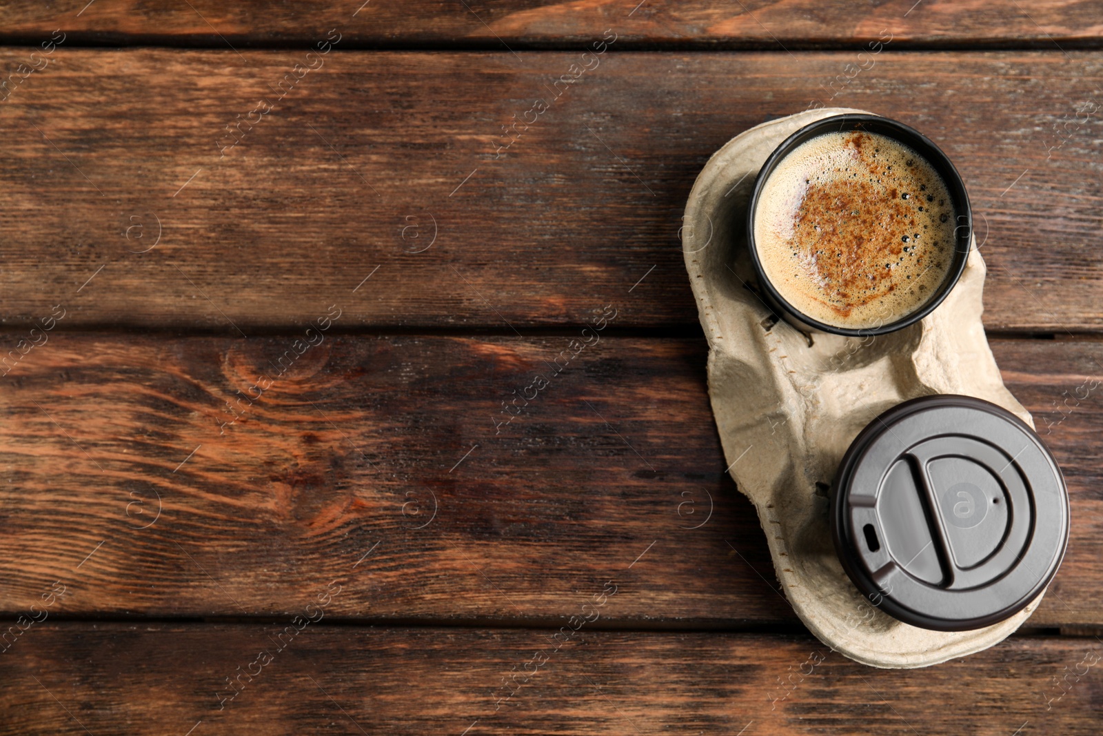 Photo of Takeaway paper cups with coffee in cardboard holder on wooden table, top view. Space for text