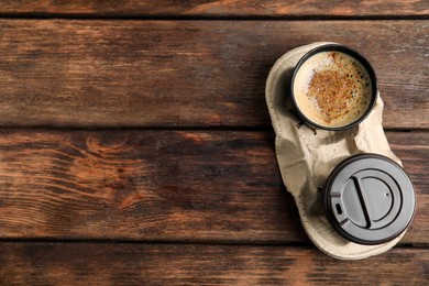 Photo of Takeaway paper cups with coffee in cardboard holder on wooden table, top view. Space for text