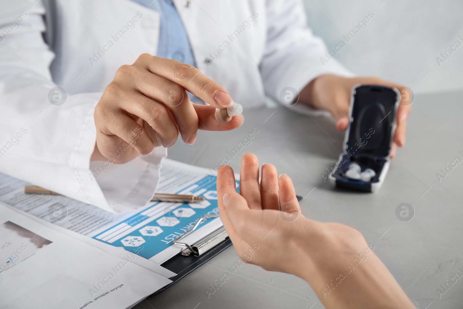Photo of Doctor giving hearing aid to patient in hospital, closeup