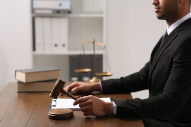 Photo of Law and justice. Closeup of judge with gavel at wooden table in office